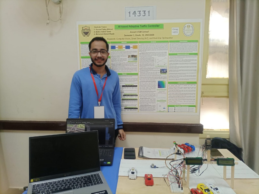 Botros presenting his AI-based Adaptive Traffic Controller project with the research poster and prototype setup on the table